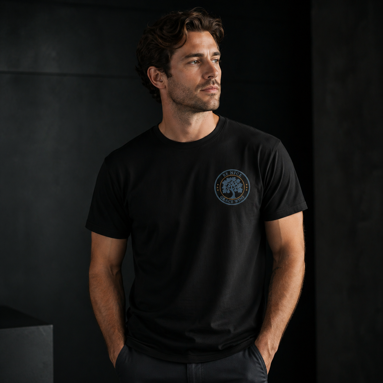 Man wearing the Fig Tree Pocket Tee in Black against a dark wall