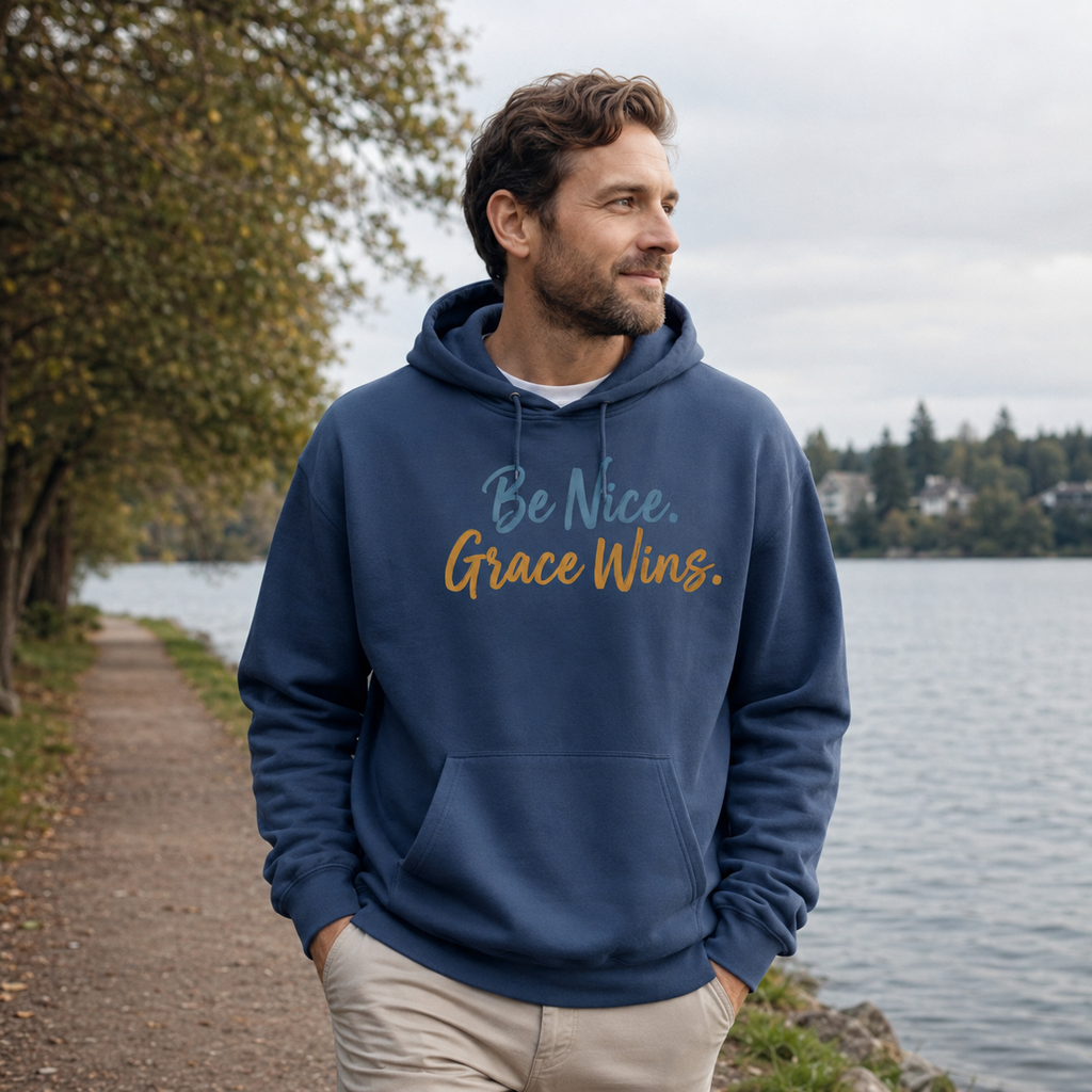 Man wearing the Be Nice Grace Wins Hoodie in Blue near the water